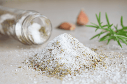 Frisch gemachtes Kräutersalz mit frischem Rosmarin im Hintergrund