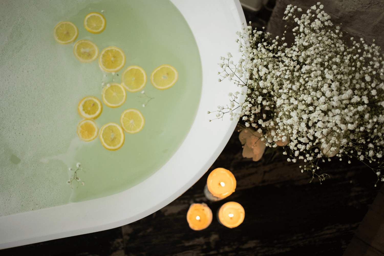 Volle Badewanne mit frischen Blumen daneben und Orangenscheiben auf dem Wasser schwimmend