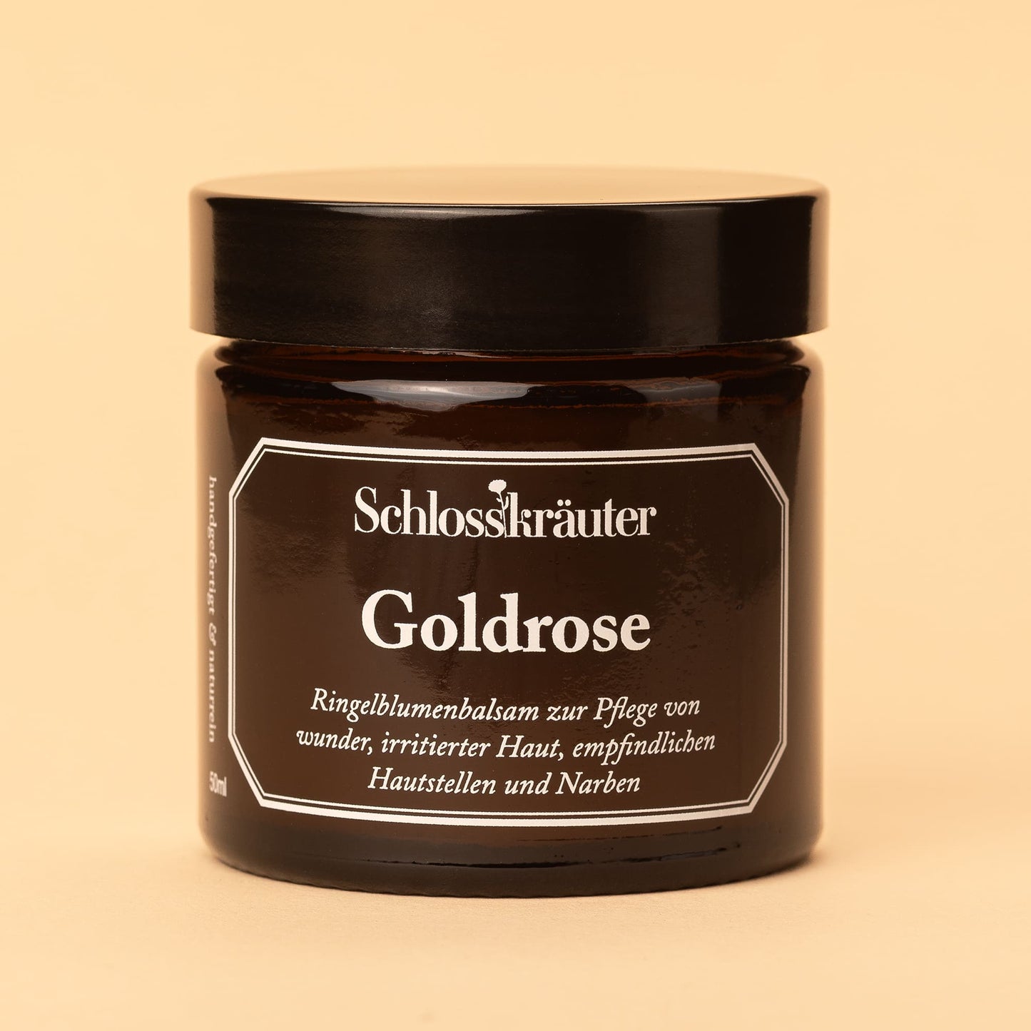 Braunes Glas mit schwarzem Deckel und Etikett „Goldrose – Ringelblumenbalsam zur Pflege von wunder, irritierter oder empfindlicher Haut“, vor hellem Hintergrund.