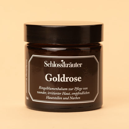 Braunes Glas mit schwarzem Deckel und Etikett „Goldrose – Ringelblumenbalsam zur Pflege von wunder, irritierter oder empfindlicher Haut“, vor hellem Hintergrund.