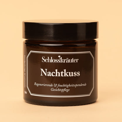 Braunes Glas mit schwarzem Deckel und Etikett „Nachtkuss – regenerierende und feuchtigkeitsspendende Gesichtspflege“, vor hellem Hintergrund.