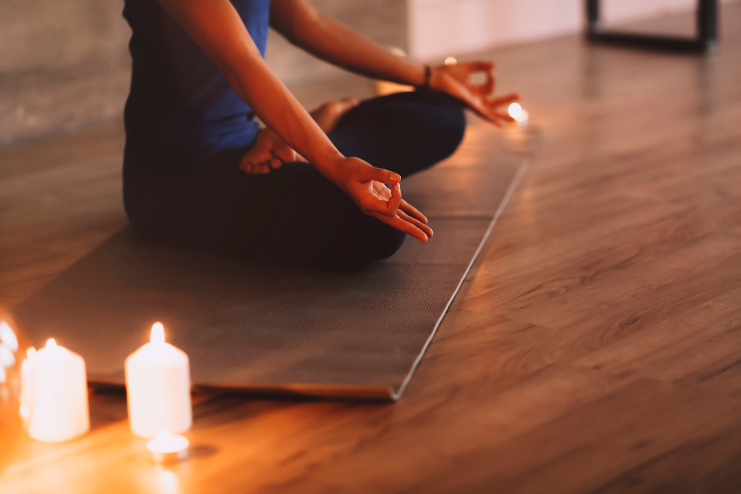 Meditierende Frau auf Yogamatte mit Kerzen